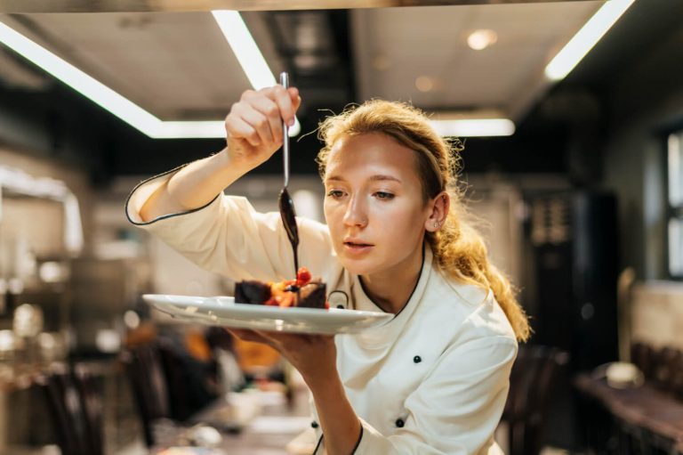 female-chef-carefully-pouring-sauce-dish